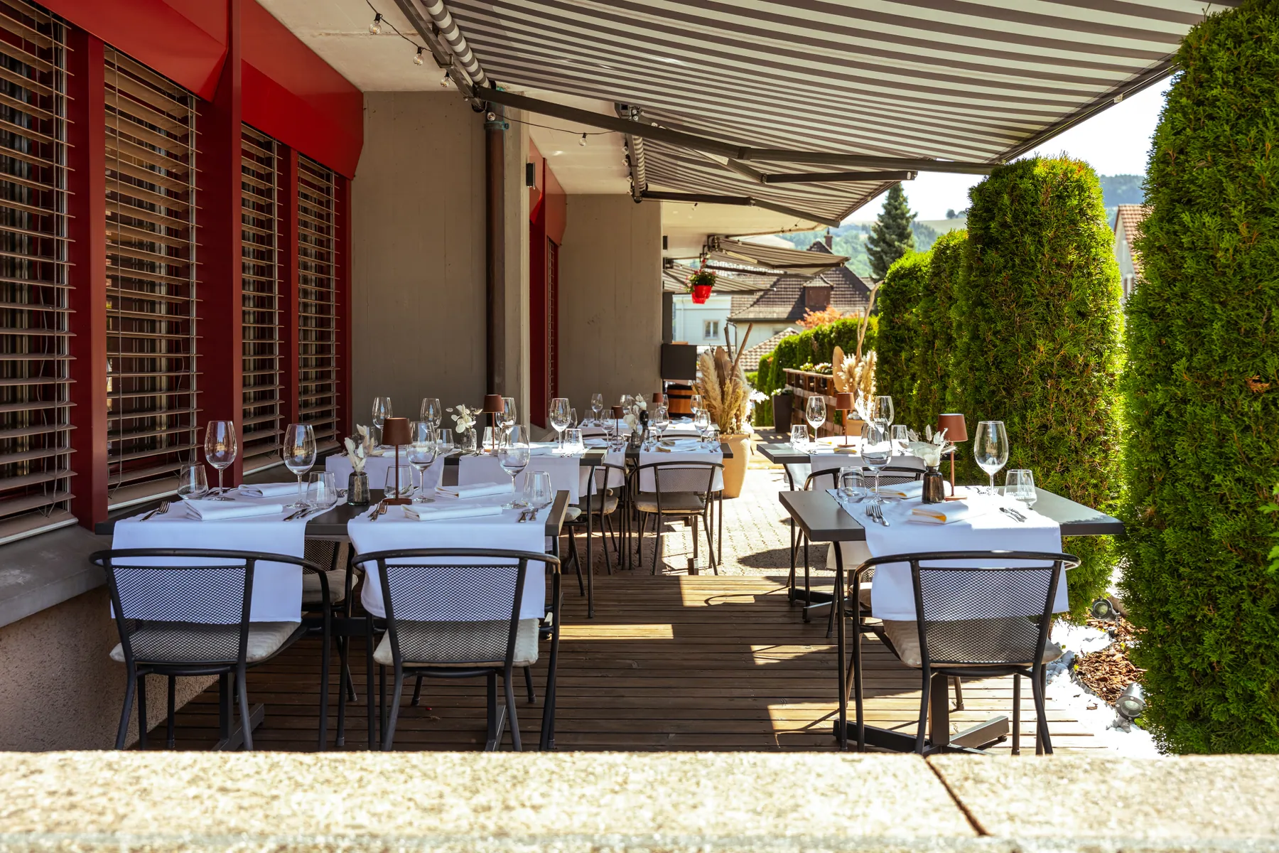 Gedeckte Restaurantterrasse unter gestreiften Sonnenstoren